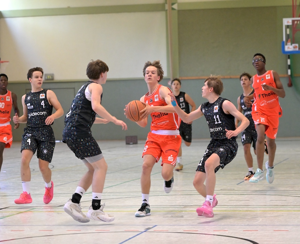 Junger Spieler im orangefarbenen Trikot dribbelt konzentriert durch die Verteidigung