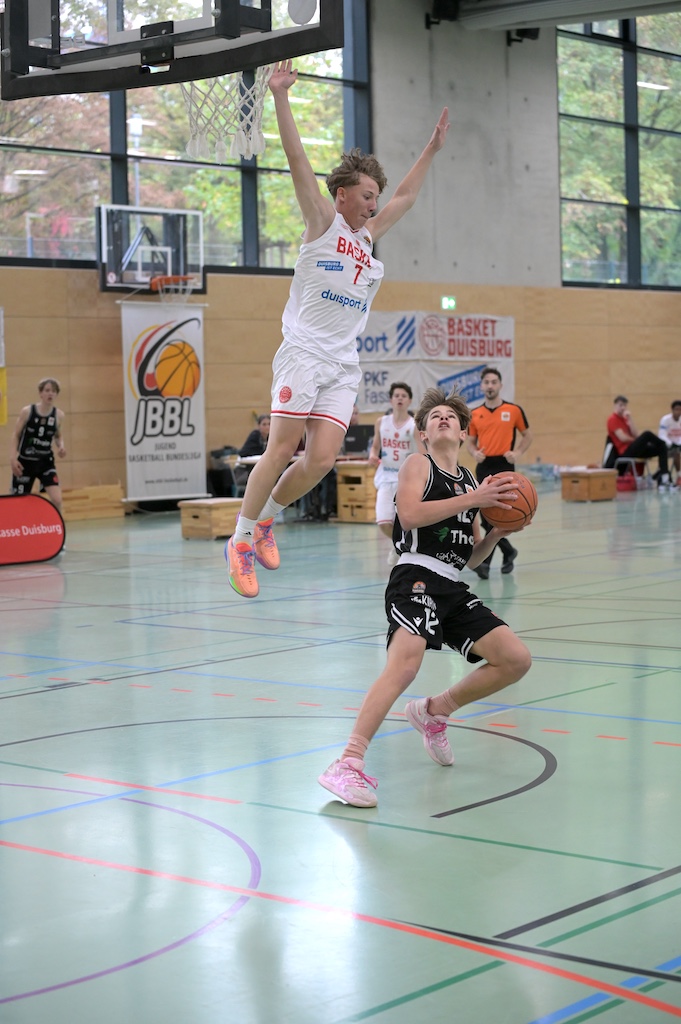Zwei junge Basketballspieler in einem spannenden Spielmoment in einer Halle