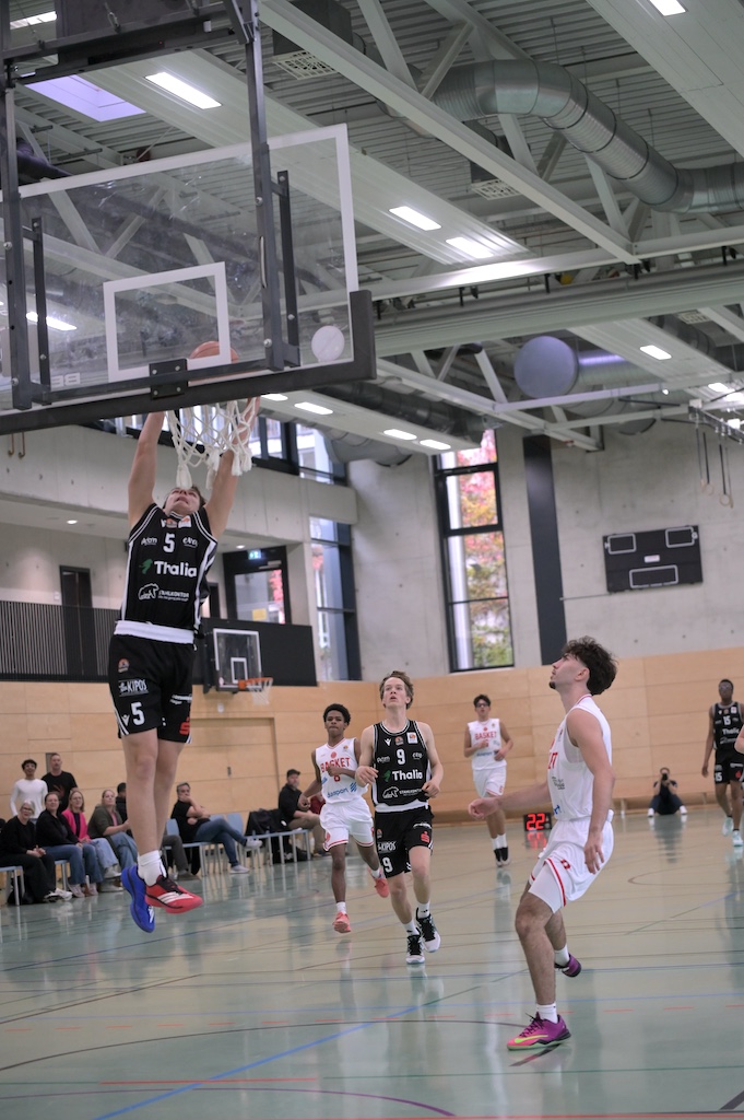 Basketballspieler in schwarzem Trikot mit Nummer 5 beim konzentrierten Korbleger