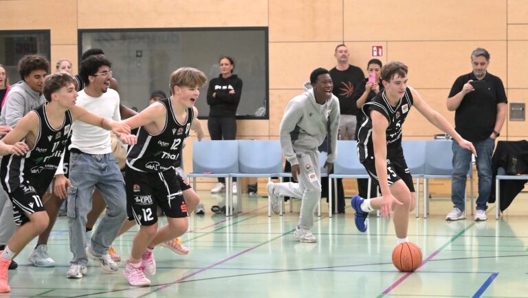 Jugendliche Basketballspieler in schwarzen Trikots beim freudigen Spiel in der Halle