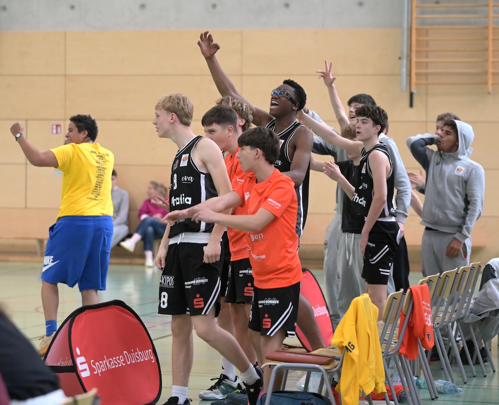 Jubelnde Basketballmannschaft in schwarzen und orangefarbenen Trikots in der Halle