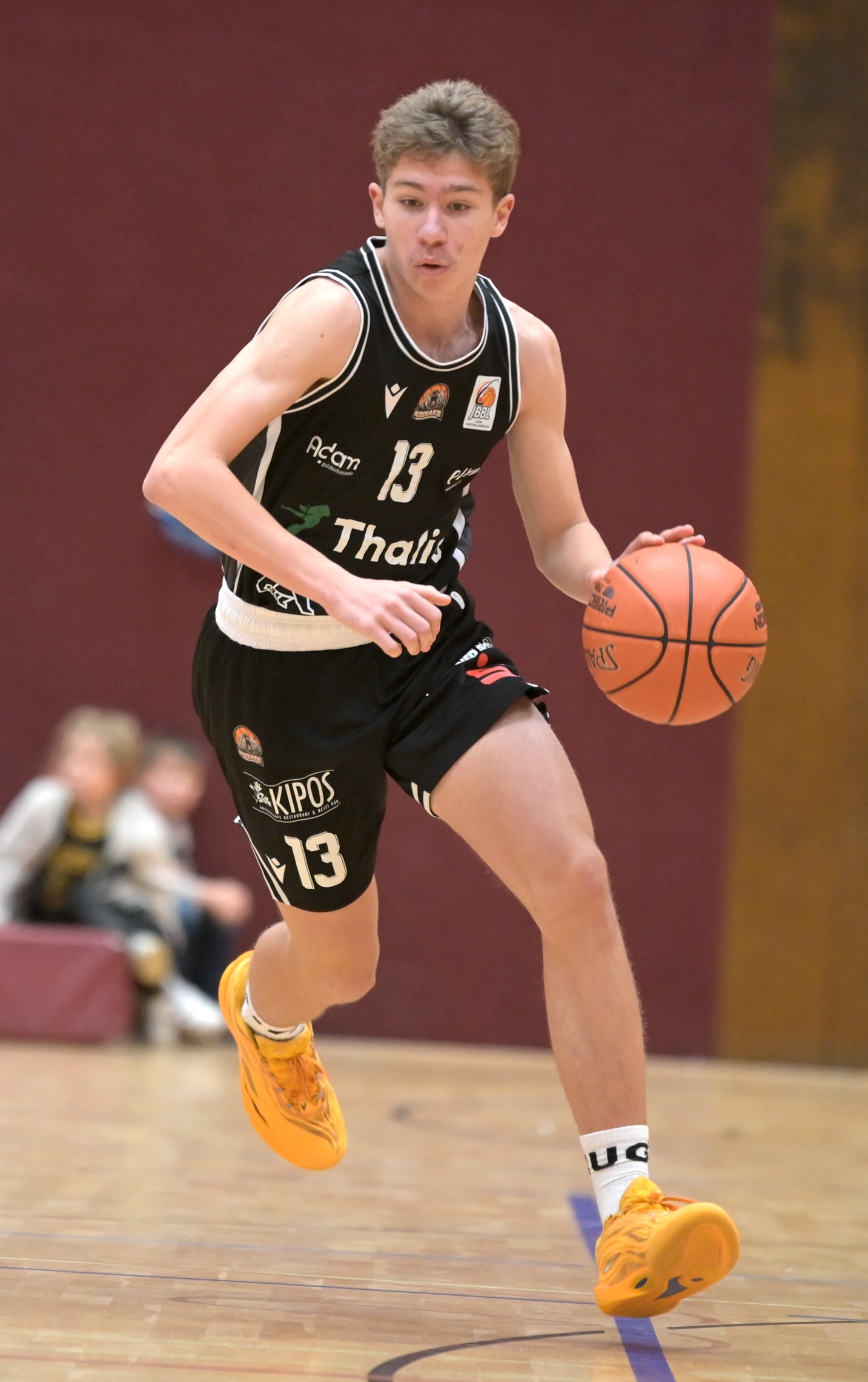 Konzentrierter Basketballspieler im schwarzen Trikot Nummer 13 mit gelben Schuhen