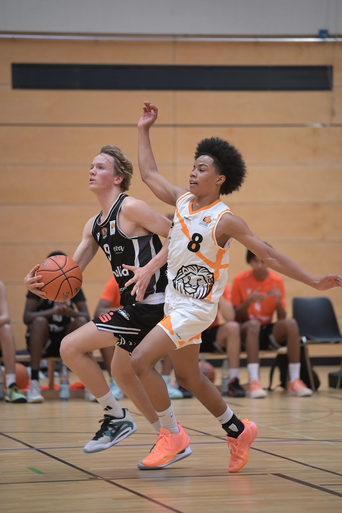 Zwei konzentrierte Basketballspieler in Schwarz und Weiss kaempfen um den Ball