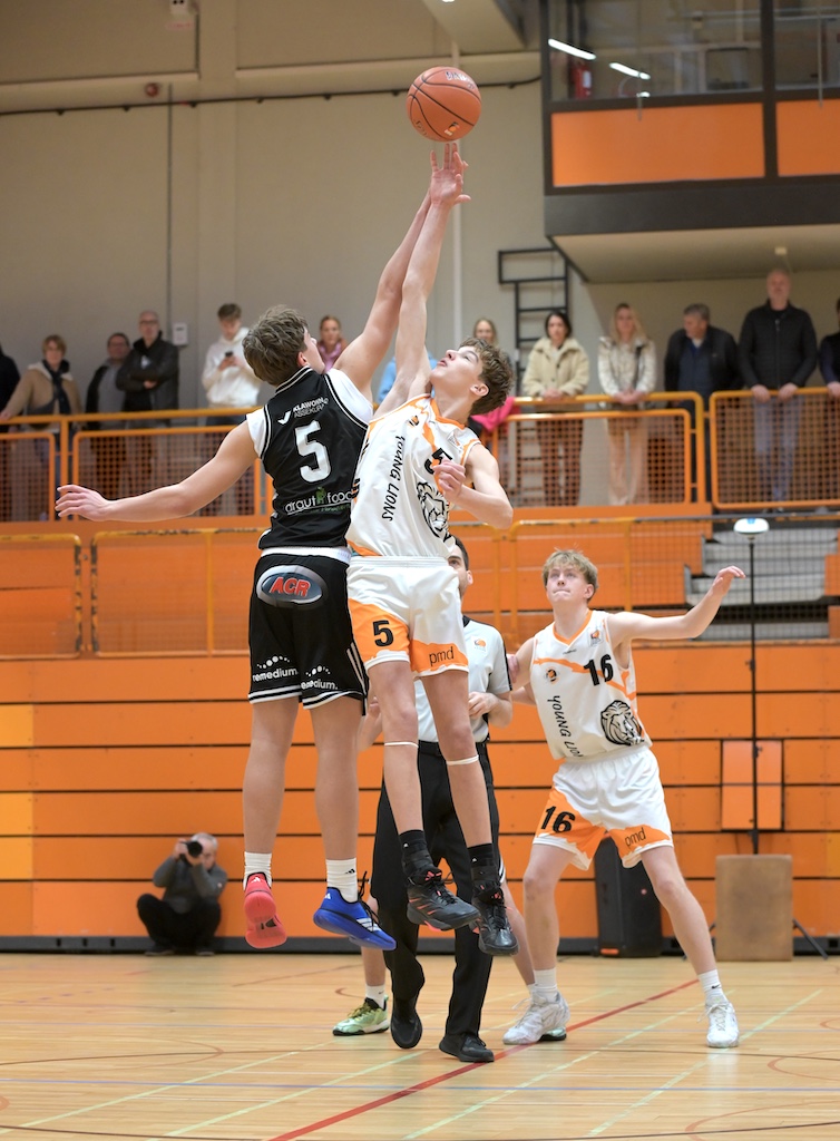 Zwei Basketballspieler springen konzentriert zum Sprungball um den orangenen Ball
