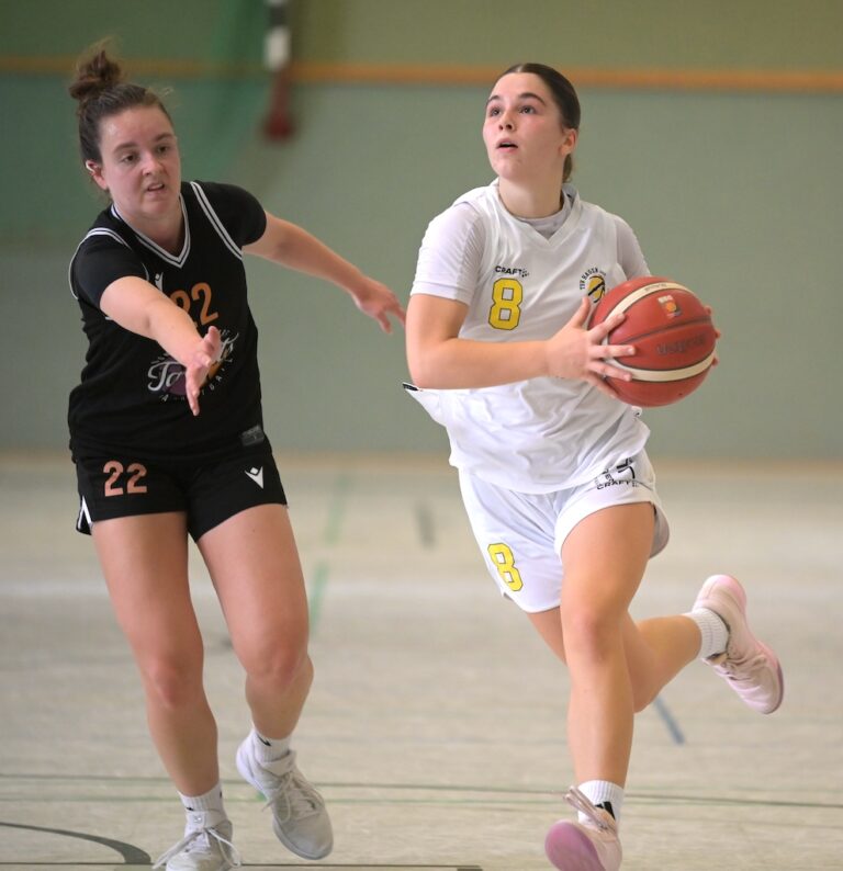 Zwei konzentrierte Basketballspielerinnen in Weiss und Schwarz kaempfen um den Ball