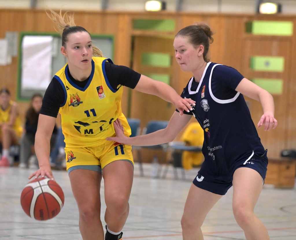 Zwei konzentrierte Basketballspielerinnen in Gelb und Dunkelblau im Zweikampf