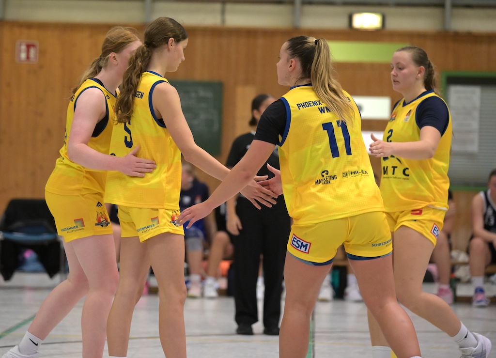 Vier Basketballspielerinnen in gelben Trikots klatschen sich konzentriert ab