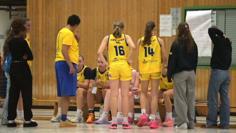 Ein Basketballteam in gelben Trikots versammelt sich waehrend einer Auszeit